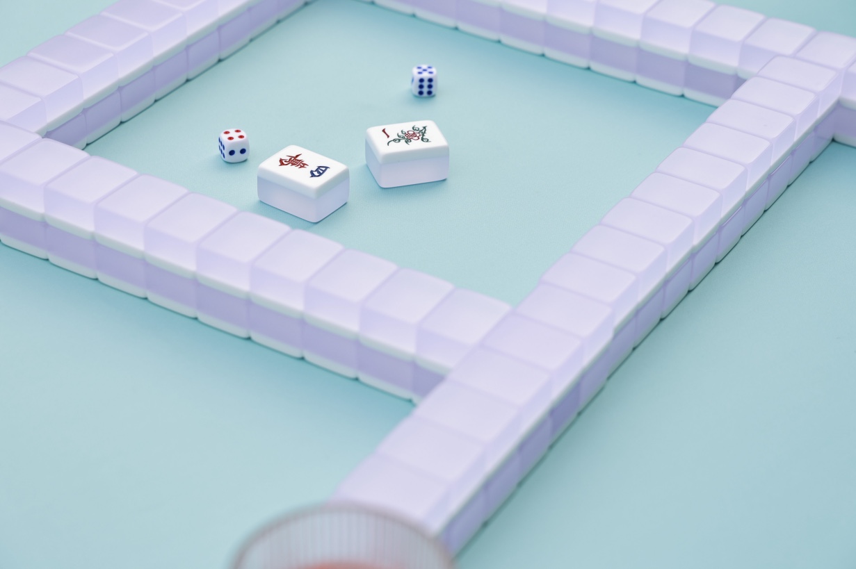 Close view of a game in progress on the green aknonr mat: a wall of tiles, two tiles and dice on the pale aqua play surface